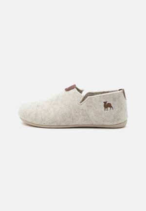 Chausson en feutre gris clair avec semelle basse, bordure en cuir marron et petit logo chien marron près du talon côté extérieur.
