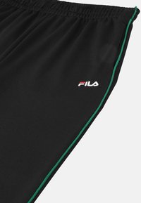 Zwarte sportieve broek van gladde stof met groene zijkanten en een klein wit en rood Fila-logo op de linkerheup.