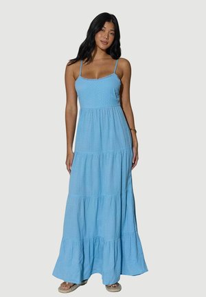 Lichtblauwe maxi-jurk met lagen en spaghettibandjes, textuurstof, een rand met gehaakte rand en een vloeiende zoom. Gecombineerd met neutrale sandalen.