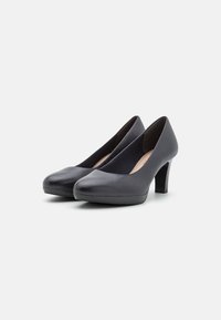 Černé kožené lodičky s kulatou špičkou, středně vysokým podpatkem a hladkým povrchem. Navrženy s elegantním siluetou a minimálním zdobením.
