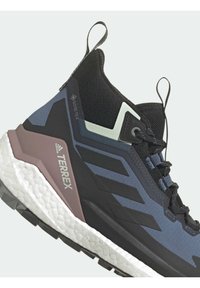 Mustat ja siniset Adidas Terrex vaelluskenkä Gore-Tex-materiaalista, nauhakiinnityksellä ja paksulla valkoisella tekstuuripohjalla.