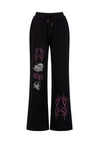 Zwarte sweatpants met een wijdere pasvorm, tribale motieven in paars en zilver, en een schedelafbeelding met de tekst "EH" op het linkerbeen.
