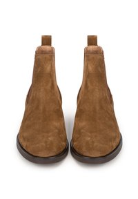 Botas Chelsea de ante marrón con una textura suave, lengüetas para facilitar el calce, paneles elásticos en los laterales y punta redondeada, apoyadas sobre una suela de goma oscura.