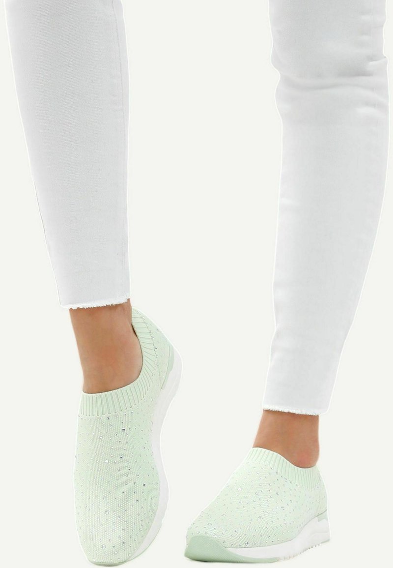 Lichtgroene instapsneakers met een geweven bovenkant en kleine met rhinestones versierde accenten. Witte rubberen zolen, getoond met witte cropped broeken.