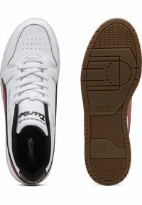 Puma obuća s gornjim dijelom od bijele kože, crnim i crvenim detaljima, perforiranim prednjim dijelom, te smešnim gumenim potplatom s teksturiranim gripom.