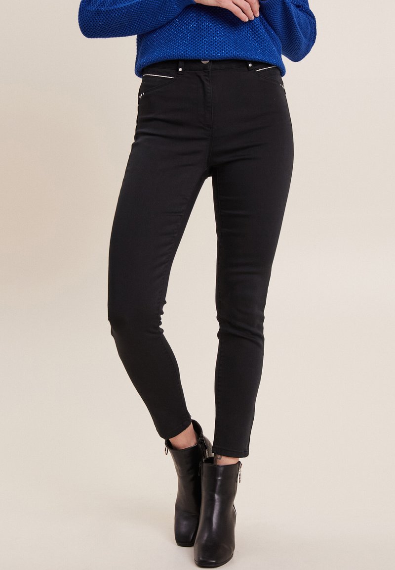 Jean skinny noir en denim, avec des poches zippées à l'avant, une taille mi-haute et un design lisse et ajusté.