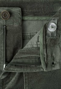 Dunkelgrüne Hose aus weichem, strukturiertem Stoff mit einem Metallreißverschluss, Knopfverschluss und innerer Taillenbandverkleidung, die die Nähte hervorhebt.