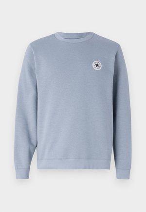 Ljusblå sweatshirt tillverkad av bomullsblandat tyg. Har rund hals, ribbade manschetter och en cirkulär logotyp på bröstet.