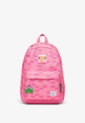 Sac à dos rose avec motif pixellisé, un écusson de mouton Minecraft près du haut et une poche avant avec des breloques tulipes pixellisées.