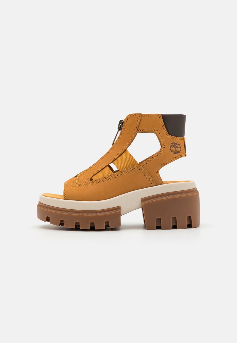 Fette sandfarbene Sandale mit Ausschnitten, Reißverschluss auf der Vorderseite, elastischem Band, gepolstertem schwarzen Fersenkragen, Timberland-Logo und dickem Profilsohle mit Blockabsatz.
