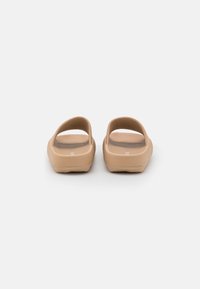 Sandali aperti color tan con una finitura opaca texture, dotati di due fasce larghe e una suola flessibile, progettati per il comfort e la facilità d'uso.