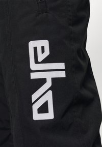 Zwarte stoffen shorts met een opvallend wit logo aan de zijkant, met een soepele textuur en nette stiksels.