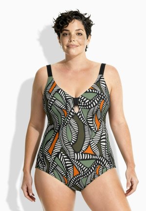 Woman with short curly hair wearing a one-piece swimsuit with black, white, green, and orange abstract leaf patterns.
