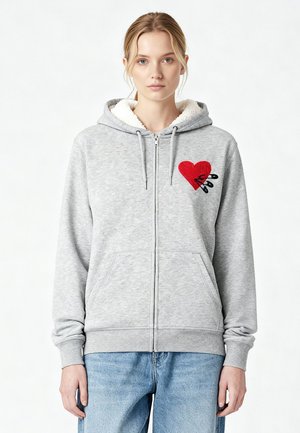 Felpa grigia con zip, con cappuccio foderato in pile e ricamo a forma di cuore rosso. Presenta tasche frontali e polsini a costine. Materiale in morbido misto cotone.