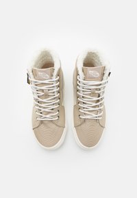 Beige høye sneakers med teksturert kanvas-overdel, hvite lisser og imitert pelsfôr rundt kragen. Gummisåle med logo-detaljer.
