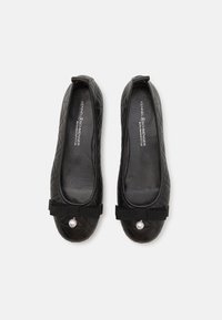 Ballerines noires matelassées avec un bout rond, ornées d'un nœud et d'un détail en perles à l'avant. Doublure intérieure lisse.