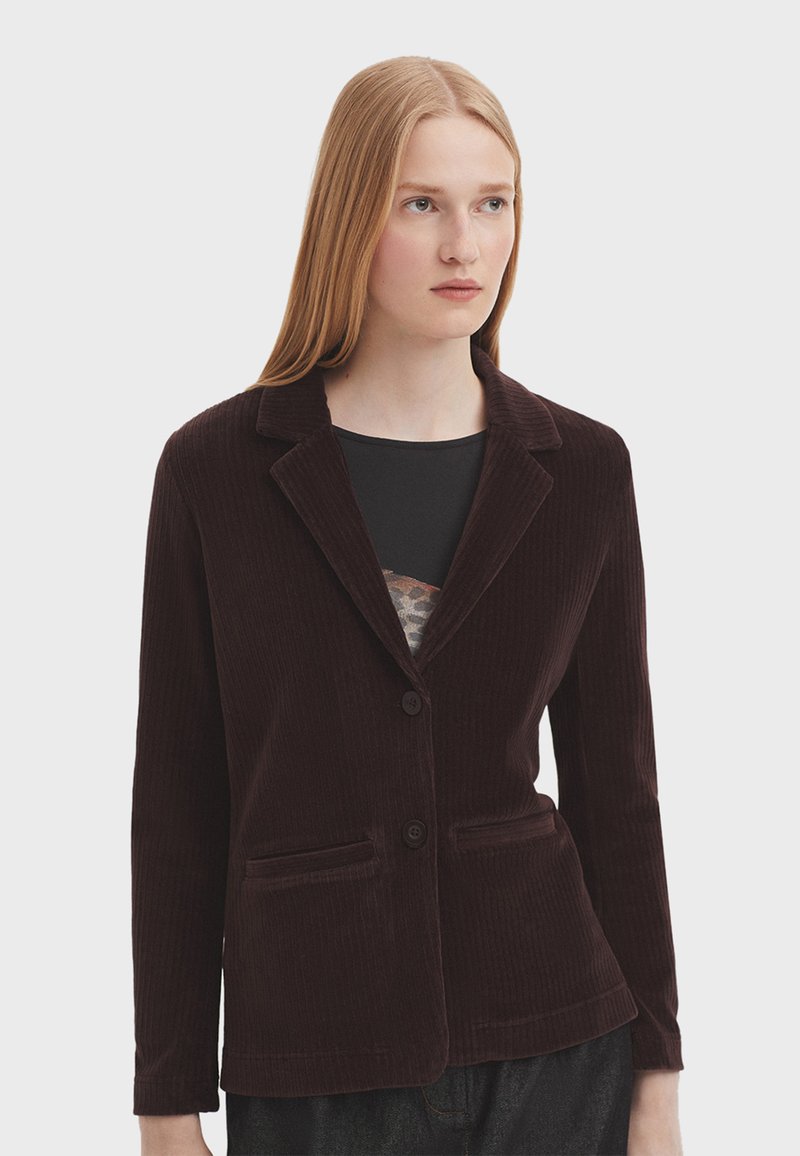 Blazer in corduroy marrone scuro con colletto a revers, due tasche frontali e chiusura con un bottone. Texture liscia con dettagli a coste fini.