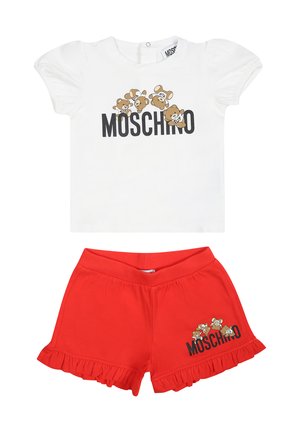 T-shirt bianca in cotone con maniche a sbuffo, caratterizzata da una grafica di un orso e il testo "MOSCHINO"; abbinata a pantaloncini rossi con volant, anch'essi con dettaglio del logo.