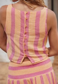 Top a rayas colorido en tonos de amarillo y rosa, con un cierre de botones en la parte posterior y un corte relajado, hecho de una suave tela texturizada.