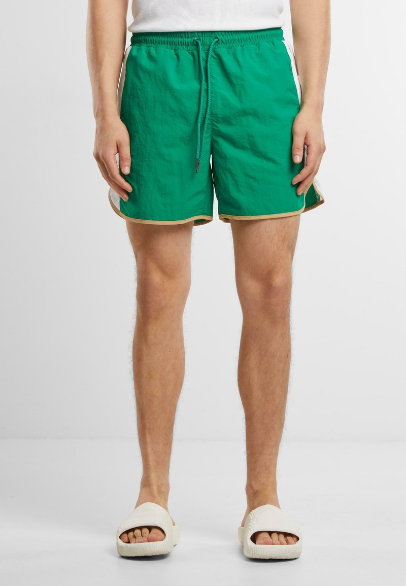 Shorts de bain verts avec une finition texturée, une taille élastique et un cordon de serrage, bord doré le long de l'ourlet et poches latérales.