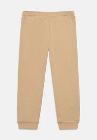 Bež bombažne trenirke z elastičnim pasom, zoženimi manšetami in mehko, gladko teksturo. Preprost dizajn, brez vzorcev ali dodatkov.