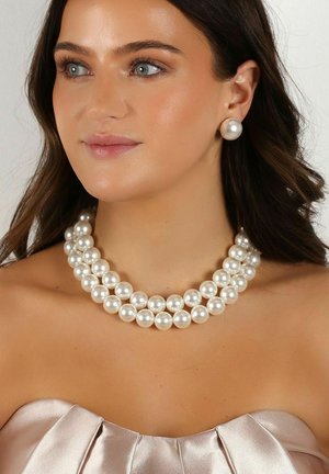 Drei Stränge glänzender weißer Perlen bilden eine Halskette, ergänzt mit passenden Perlensteckohrringen. Die glatten, runden Formen steigern die Eleganz.