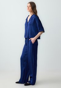 Navyblauw linnenmix outfit met een cropped top met korte mouwen en losse, wijde broekspijpen. Beide hebben een subtiele textuur.