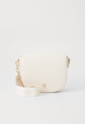 Lille cremefarvet crossbodytaske med bredt stofrem og et guldtonet "TH" logo på frontklappen.