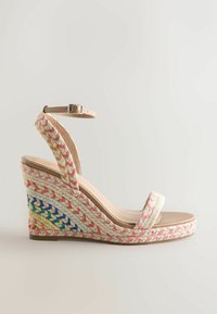 Sandale compensée beige avec talon tressé multicolore, bride de cheville avec boucle et une seule bride sur les orteils, sur fond neutre.