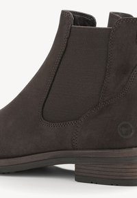 Dark brown suede ankle boot with elastic side panels, round toe, and wooden heel. Features a subtle logo on the outer side.