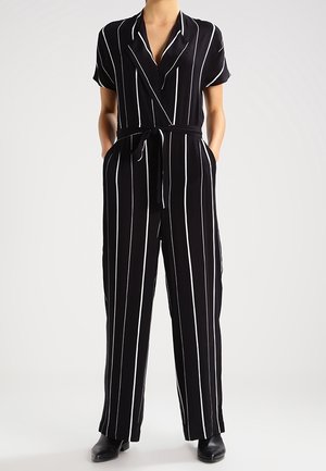 Black jumpsuit with white vertical stripes, short sleeves, wrap front, and a matching belt. Features loose-fit trousers and a smooth texture.