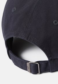 Gorra de béisbol de color azul marino oscuro, hecha de algodón, con una superficie texturizada, detalles cosidos y un hebilla de metal ajustable en la parte posterior.
