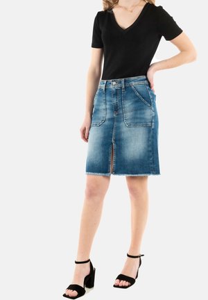 Jeansbleistiftrock mit einem vorderen Schlitz, rohem Saum und verblasster blauer Waschung. Kombiniert mit einem schwarzen V-Ausschnitt-Shirt und schwarzen High-Heel-Sandalen.