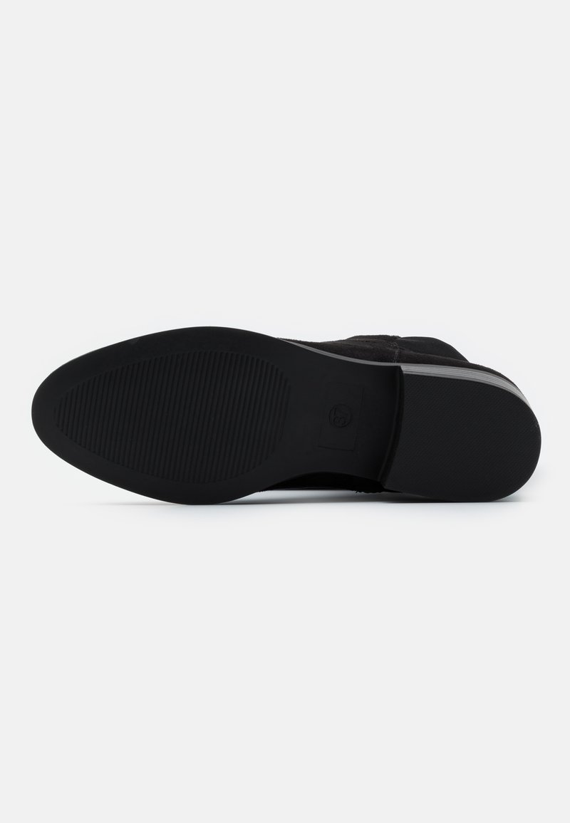 Schwarze Schuhsohle mit einer strukturierten Gummioberfläche, die Rillen für Grip und eine abgerundete Form aufweist, hergestellt aus langlebigen Materialien.