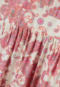 Tissu floral multicolore présentant des motifs de paisley et de fleurs complexes. Fond crème clair avec des détails de texture froncés.