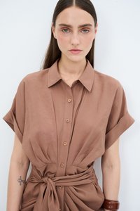 Camicia marrone a maniche corte con colletto, chiusura frontale con bottoni e cravatta annodata in vita; realizzata in tessuto morbido e leggero.