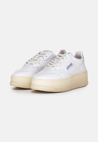 Witte leren sneakers met een geperforeerde neus, crèmekleurige zool, ronde vorm en subtiele branding aan de zijkant. Klassieke vetersluiting.