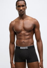 Fekete boxeralsó finoman mintázott textúrával, elasztikus derékpánt logó részletezéssel, és testhezálló kialakítással, amely kiemeli az alakot.