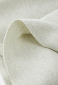 Tessuto morbido di un grigio chiaro, con una texture liscia e un sottile motivo a spina di pesce, che presenta un bordo leggermente sfilacciato per un tocco di dettaglio.
