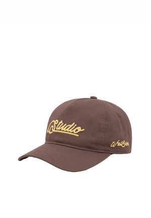 Braune Baseballkappe mit gelbem, aufgesticktem Schriftzug „Studio“ auf der Vorderseite und kleinerem Text an der Seite vor weißem Hintergrund.