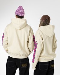 Crím színű kapucnis pulóverek, rózsaszín grafikus szöveggel az ujjakon, fekete nadrággal párosítva, arany öltésekkel és két hátsó zsebbel. Az egyiküknél rózsaszín sapka, a másiknál barna sapka van.