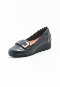 Mocasín negro de cuero con una correa texturizada y un acento de hebilla en tono dorado. Cuenta con un tacón cuña y suela de goma para mayor tracción.