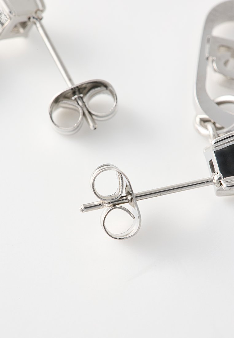 Boucles d'oreilles en argent au design en boucle et à fermeture à tige. Présentent une finition métallique brillante et des détails complexes sur les boucles.