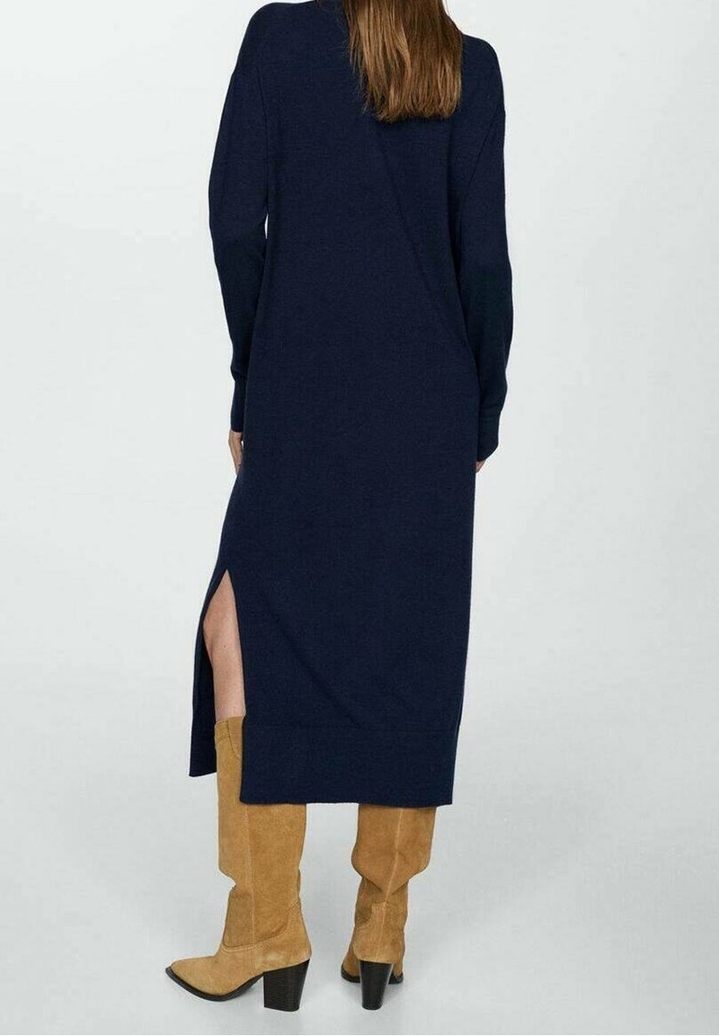 Vestido de punto de manga larga color marino con abertura lateral, combinado con botas de ante marrón claro de caña alta con tacones cuadrados. Textura suave, ajuste relajado.