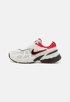 Nike sneakers hebben een bovenwerk van witte mesh, rode accenten, een zwarte zool met rode details en een gevoerd ontwerp voor ondersteuning.