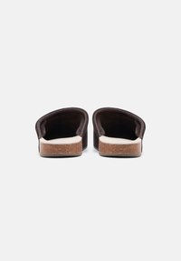 Καφέ σουέντ παντόφλες που φοριούνται εύκολα, με απαλό μπεζ εσωτερικό πάτο και υφασμένο τακούνι φελλού, με στρογγυλεμένη ανοιχτή πίσω σχεδίαση.