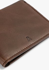 Cartera de cuero marrón con un acabado texturizado, diseño plegado y un pequeño detalle en relieve de calavera y tibias cruzadas en una esquina.