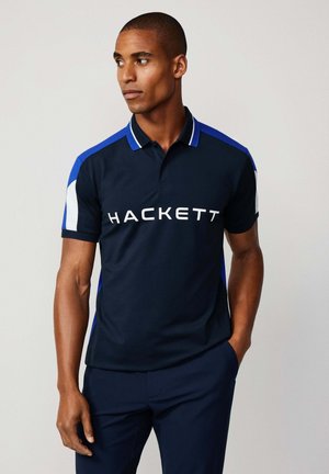 Marineblaues Poloshirt mit blauen und weißen Akzenten. Verfügt über einen Kragen und ein großes "HACKETT"-Logo in Weiß auf der Vorderseite. Glatte Stofftextur.