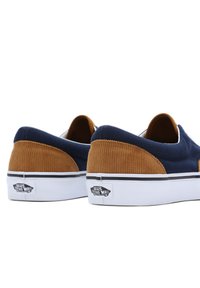Lærreds slip-on sko med en marineblå overdel, kordfløjl tan detaljer, hvide gummisål og sort logo mærke på hælen.