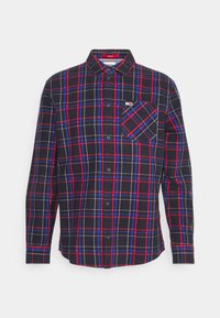 Koszula z długim rękawem zapinana na guziki w czarno-czerwono-niebiesko-białą kratę, z kieszenią na piersi i małą naszywką z logo.